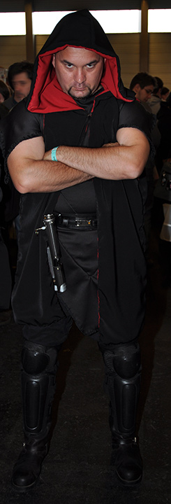 F.A.C.T.S. 2010 — Homme aux bras croisés vêtu de noir et encapuchonné, sabre lumineux à la ceinture